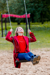 年轻女孩在秋天公园的游乐场上图片