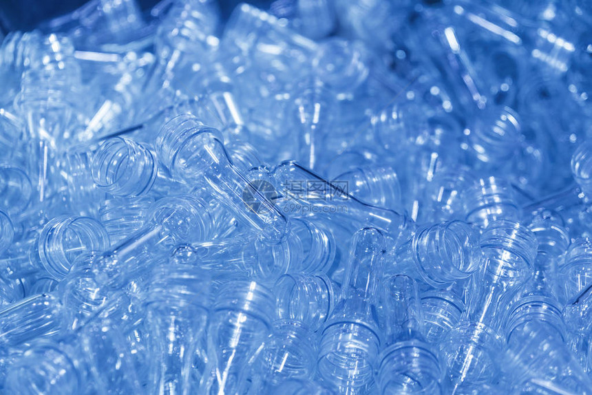 在浅蓝色场景中吹散塑料瓶工艺的PET瓶的预形状集装箱制造加图片