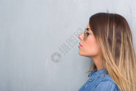 年轻的成年女在灰色的墙上戴着复古的太阳镜图片