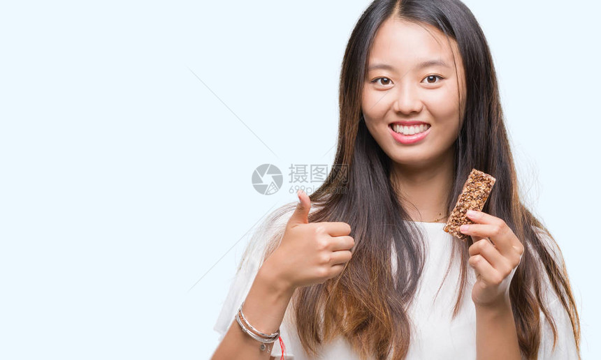年轻的亚洲女在与世隔绝的背景下吃着充满活力的巧克力棒图片