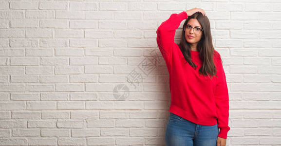 站在白砖墙上站着的年轻黑发女人迷惑和疑惑不解图片