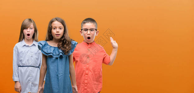 一群橙色背景中的男孩和女孩惊恐地惊恐地脸色惊恐图片