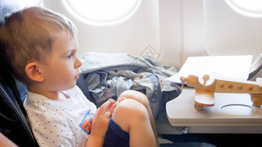 坐在飞机上看小玩具双翼飞机的可爱小孩男近图片