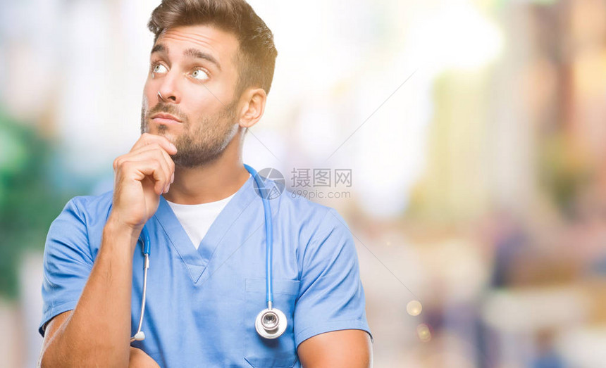 年轻英俊的外科医生在孤立的背景下用手托着下巴思考问题图片
