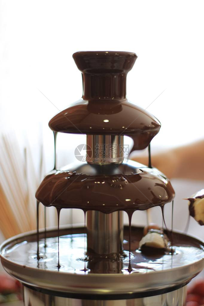 巧克力喷泉中滴落的巧克力下的一根棍子上的水果庆祝活动中美图片