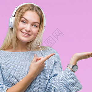 年轻caucasian女子在孤立的背景中听到戴耳机的音乐图片