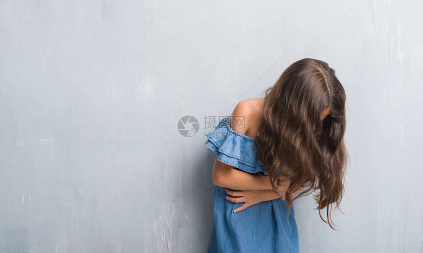 年幼的西班牙小孩在灰墙上用手摸着肚子图片