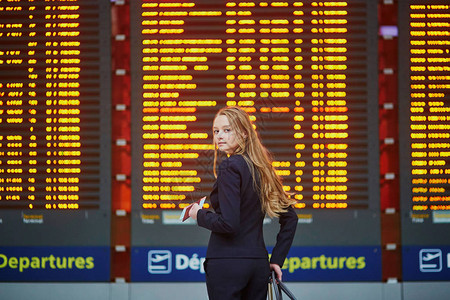 国际机场女青年在靠近大型信息显示器的国图片