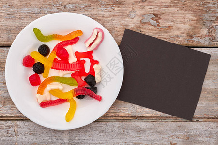 盘子里有多彩的咀嚼糖果各种果冻糖果和黑纸卡图片