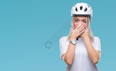 身着骑自行车安全头盔的金发年轻女郎在孤立的背景下被亲手盖住图片