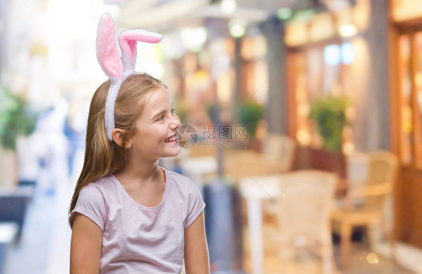 穿着复活节兔子耳朵的年轻美女在孤立的背景中带着笑容和自然的表情向着一边看图片
