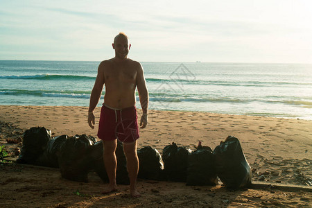 欢乐的游客站在沙滩上在海面和日落背景图片