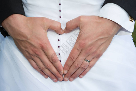 新娘和新郎手与结婚戒指在白庆典图片