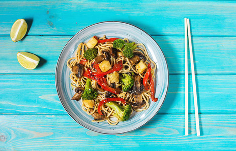 蓝色木制背景上的亚洲豆腐荞麦面碗顶视图图片