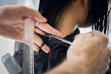 发型师用剪刀缝合在沙龙剪客户的图片