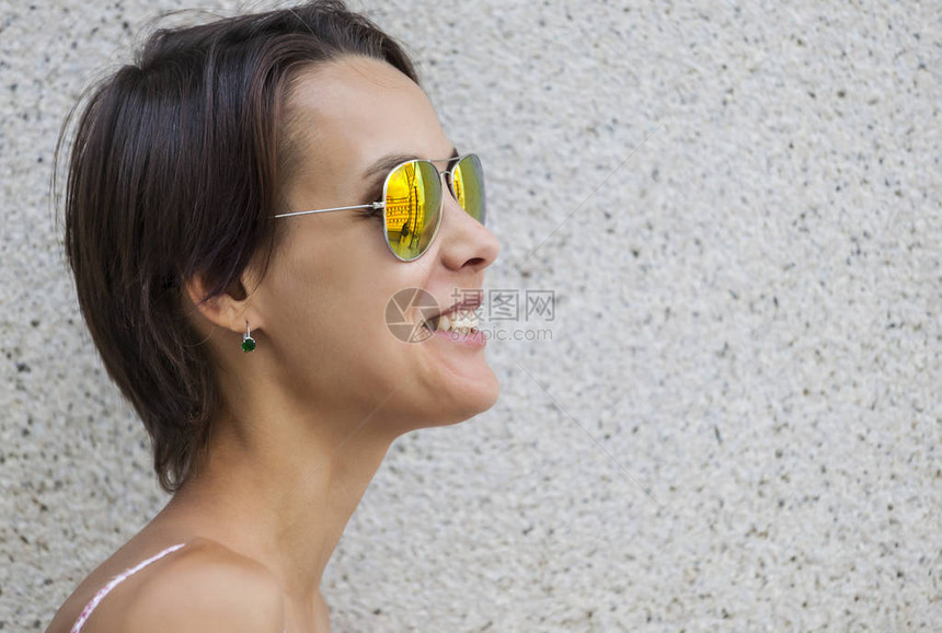 一个戴眼镜的苗条女人站在城市街道上长着短头发的黑发美女在墙壁背景下笑了起图片