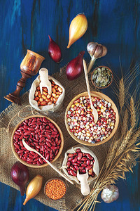 芸豆绿豆红芸豆白豆棕豆印度玉米南瓜子扁豆洋葱大蒜小麦芽在深蓝色木制图片