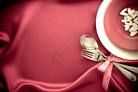 叉子和勺子放在红丝织物上图片