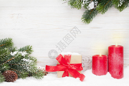 圣诞礼品盒蜡烛和木墙前有雪覆盖的fir树枝图片