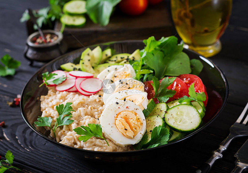 新鲜蔬菜健康沙拉西红柿鳄梨黄瓜萝卜鸡蛋芝麻菜和碗上的燕麦图片