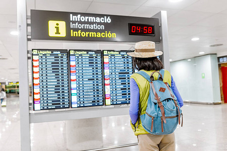 在国际机场看航班信息时间表板的亚洲图片