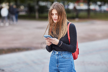 一个年轻的俄罗斯女孩正在电话上输入信息莫斯科秋天一个女孩写短信在社图片
