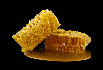 蜂蜜梳与蜂蜜隔离在黑色背景上天然图片