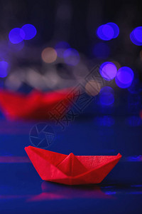 折纸船对抗模糊的灯光图片