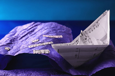 折纸船在仿造纸张的波浪上图片