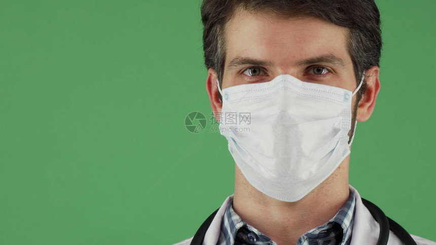 一位戴着防护医用口罩的男医生在绿色键背景上自信地摆姿势的滑动裁剪肖像戴着面具的医务人员图片