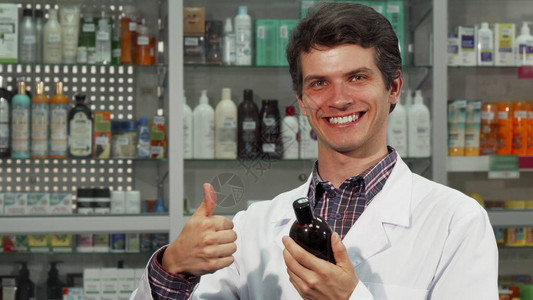 一位快乐英俊的男药剂师在他的药房检查了待售产品的标签后图片