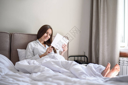 妇女用平板材料躺在床图片