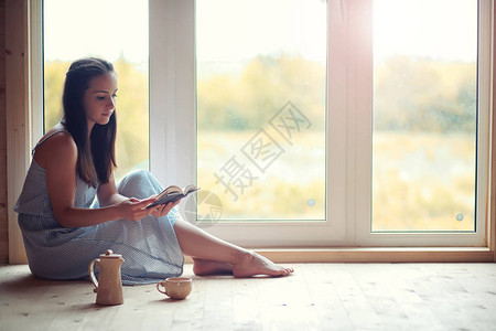 一个女孩在房子的窗户上看书图片