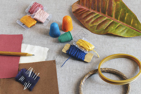 秋叶和米色织物背景上的刺绣工具图片