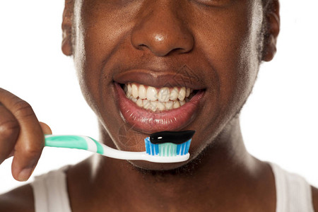 一个快乐的年轻皮肤黑皮肤男人的肖像带着牙刷和黑牙糊图片