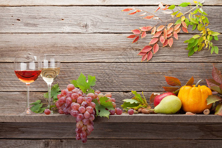 在木墙前有南瓜葡萄苹果梨子葡萄酒和彩色叶子的秋季生活卡片图片