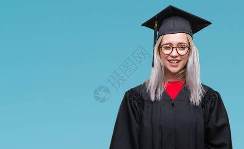 身着毕业制服的金发年轻女郎在孤立的背景上眨眼以感的表情快乐和快乐图片