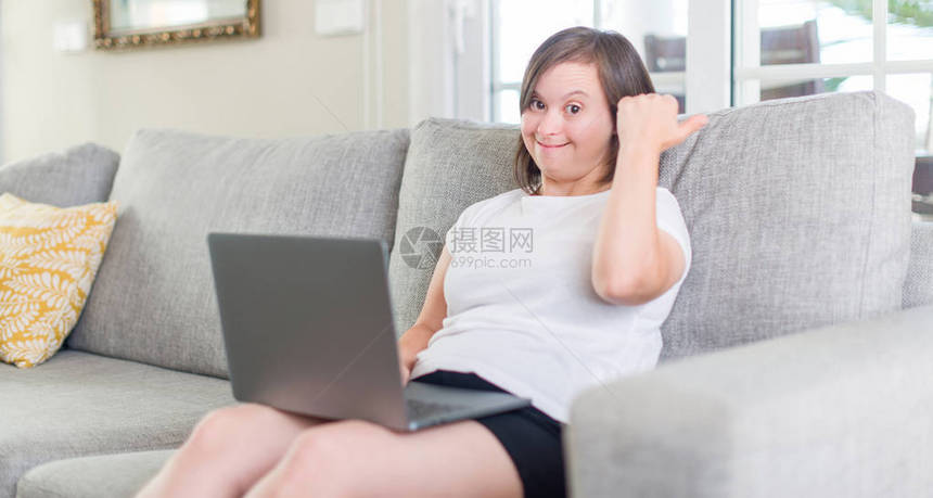 唐氏综合症女在家使用电脑笔记本电脑指着并用拇指向上展示图片