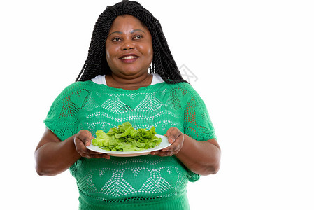 电影演播室的一张照片快乐的非洲胖黑女人微笑和思考而同时拿着生菜在白图片