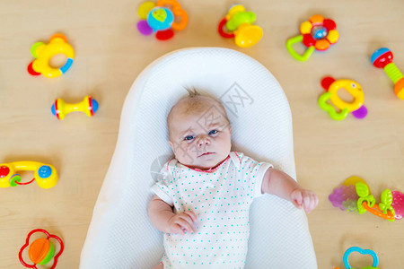 可爱的新生婴儿玩很多五颜六色的拨浪鼓玩具图片
