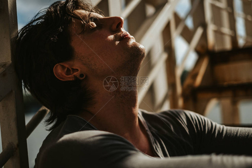 帅哥坐在楼梯上闭着眼睛晒日光浴阳图片