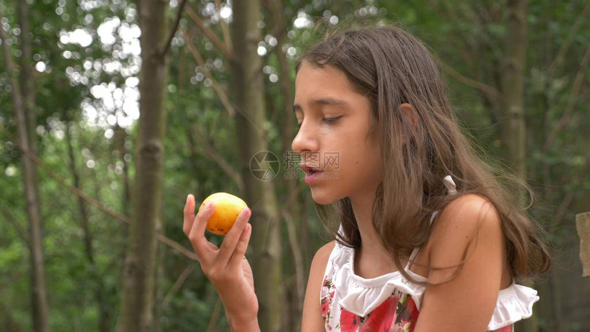 可爱的小女孩黑发吃水果和聊天图片