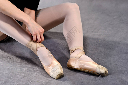在灰色背景的芭蕾舞学校将芭蕾舞女的脚图片