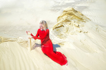 在沙漠中穿着红色连衣裙的金发女郎图片