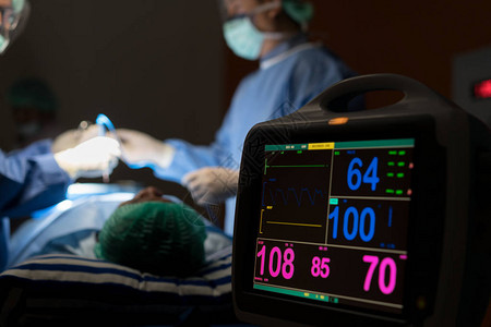 医院手术急诊室心电图显示患者心率与背景模糊的外科医生团队健图片