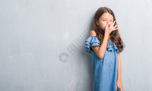 长在灰墙上的年轻西班牙小孩闻到一些臭味恶心难以忍受的气味图片
