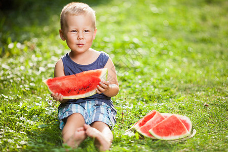 可爱的小孩坐在户外吃一片西瓜图片