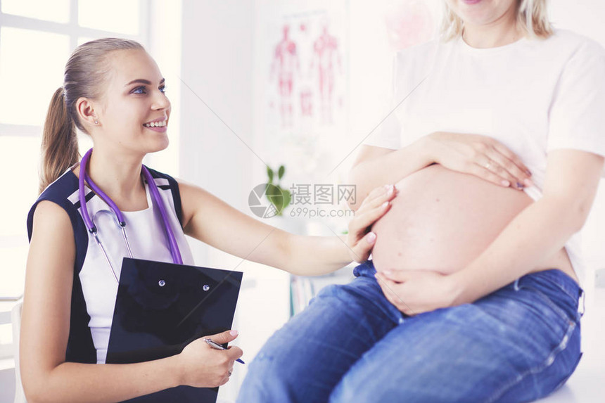 在诊所检查孕妇的年轻女医生图片