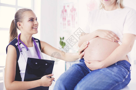 在诊所检查孕妇的年轻女医生背景图片