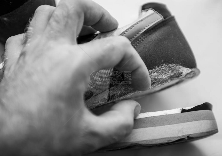 男挂着一只鞋底破损的运动鞋的黑白图像图片